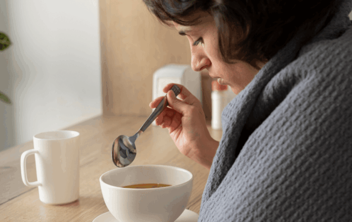 Frau isst Suppe bei Erkältung